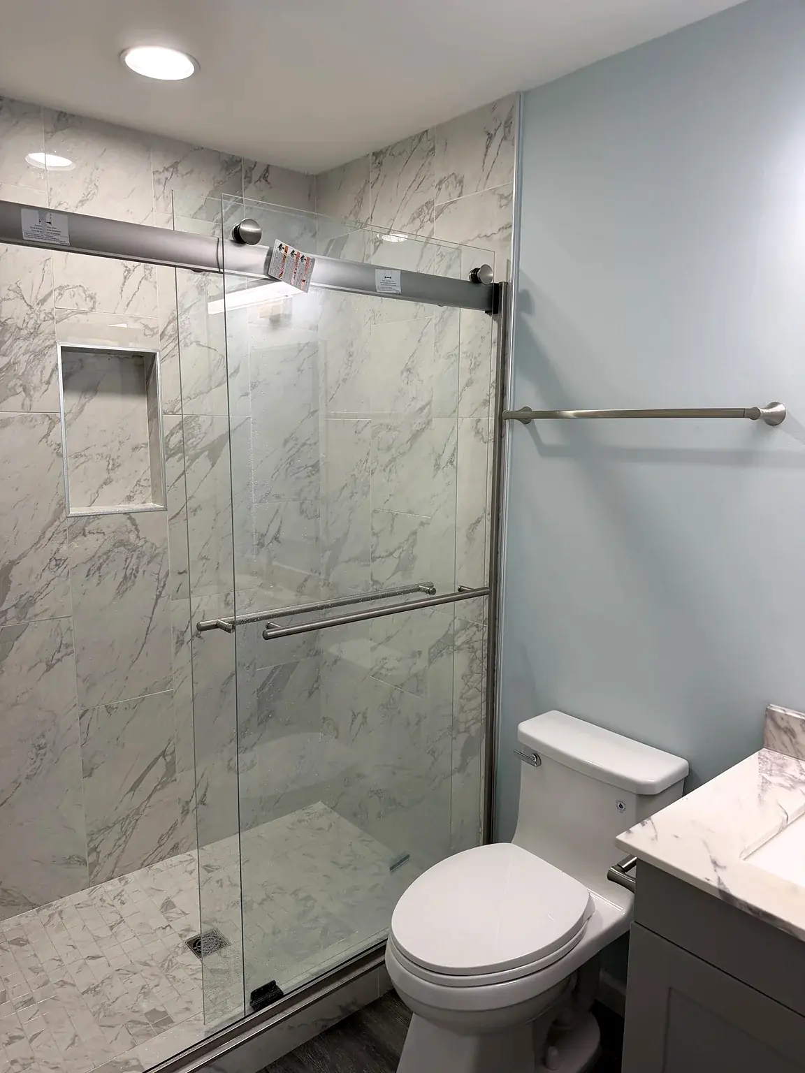 Finished bathroom with marble-look shower tile, recessed niche and sliding glass enclosure in Prince William Commons, Woodbridge, Virginia